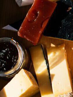 a wooden cutting board topped with cheese and crackers