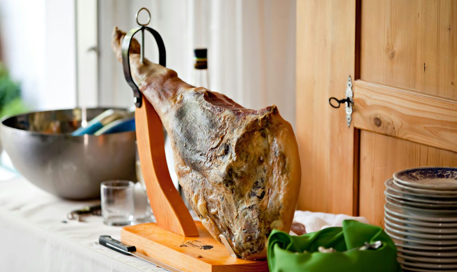 A beautifully displayed cured ham on a wooden stand in a bright kitchen setting, perfect for gourmet dining.