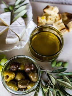 Sardines in a tin with greens and bread on a white plate, perfect for gourmet cuisine.
